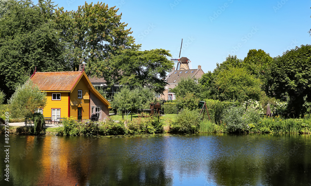 Beautiful idyllic lake with windmill background in old countryside town - Ravenstein, Netherlands, Noord-Brabant