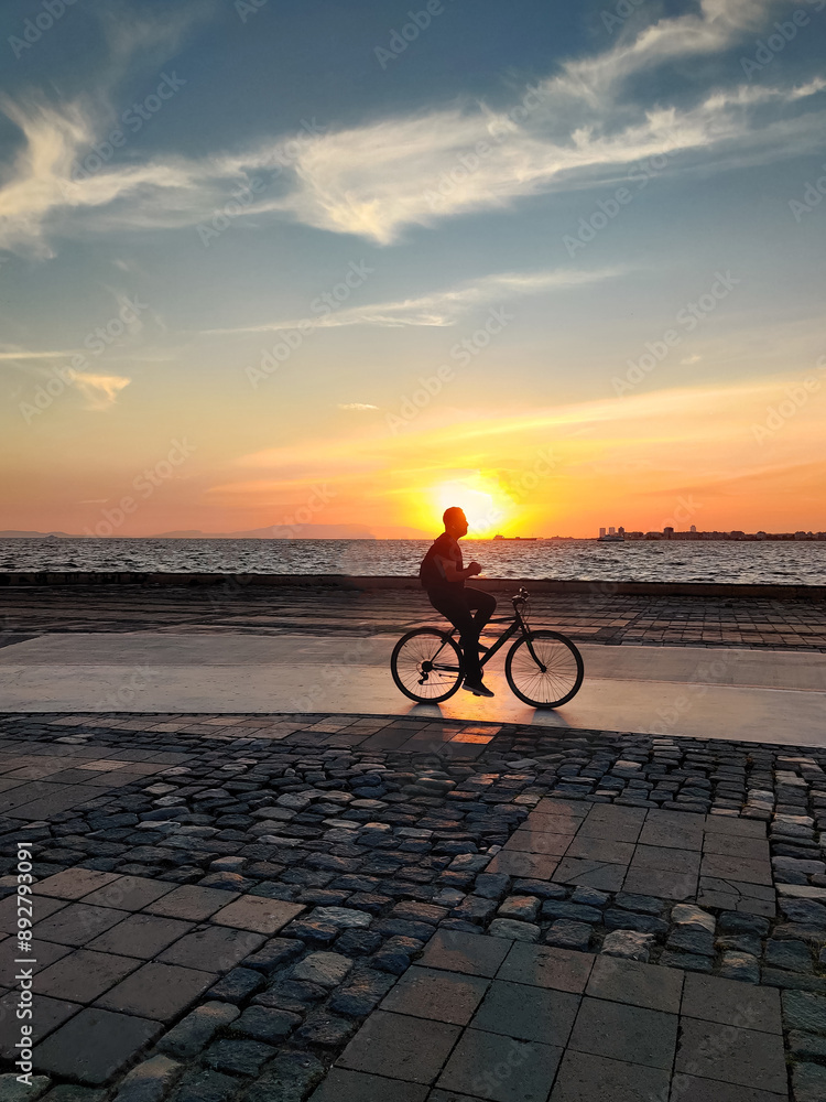Fototapeta premium man riding a bicycle beautiful landscape of sunset on the sea beach