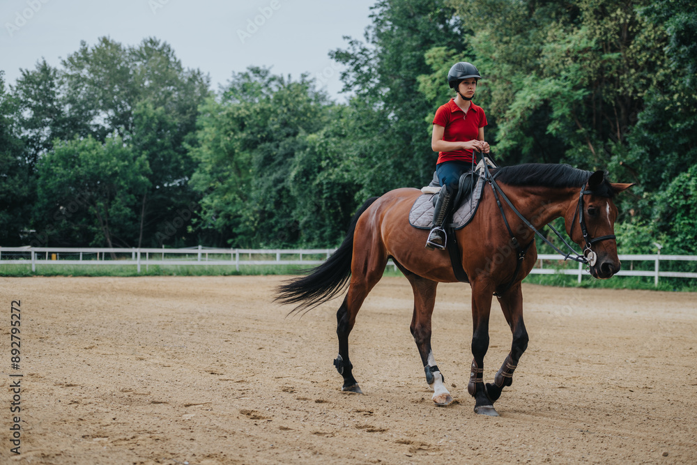 Young equestrian riding a horse at a ranch in an outdoor arena. The rider is wearing safety gear and enjoying the calm ambiance. Young equestrian riding a horse at a ranch in an outdoor arena. The rider is wearing safety gear and enjoying the calm ambiance.