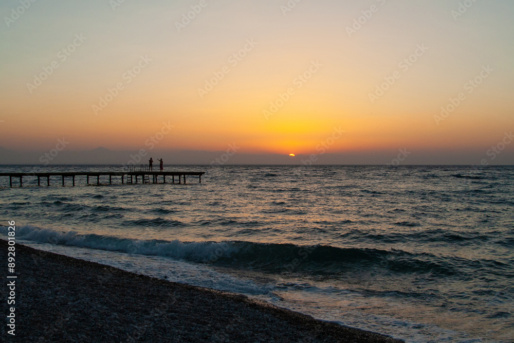 silhouette of people walking along the sea beach pier at sunset silhouette of people walking along the sea beach pier at sunset