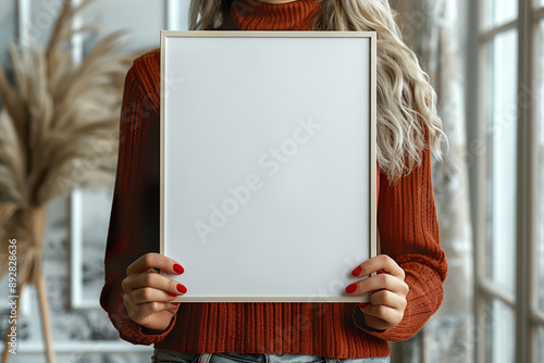 A pair of woman hands holding a light wooden vertical frame mockup 