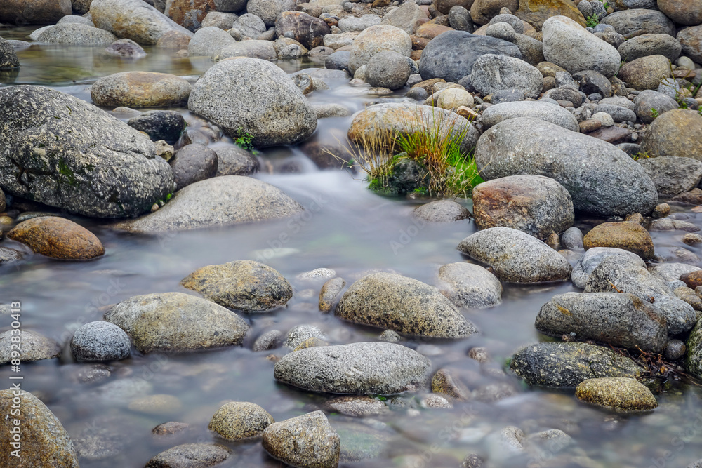A low-flowing river with banks full of round stones A low-flowing river with banks full of round stones