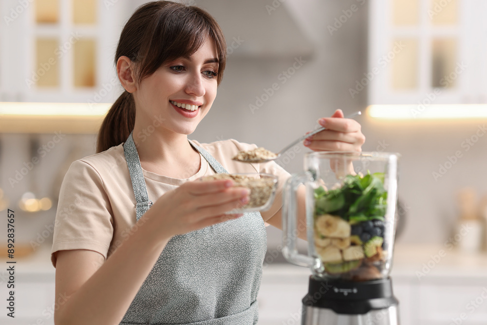 Young woman making delicious smoothie with blender in kitchen Young woman making delicious smoothie with blender in kitchen