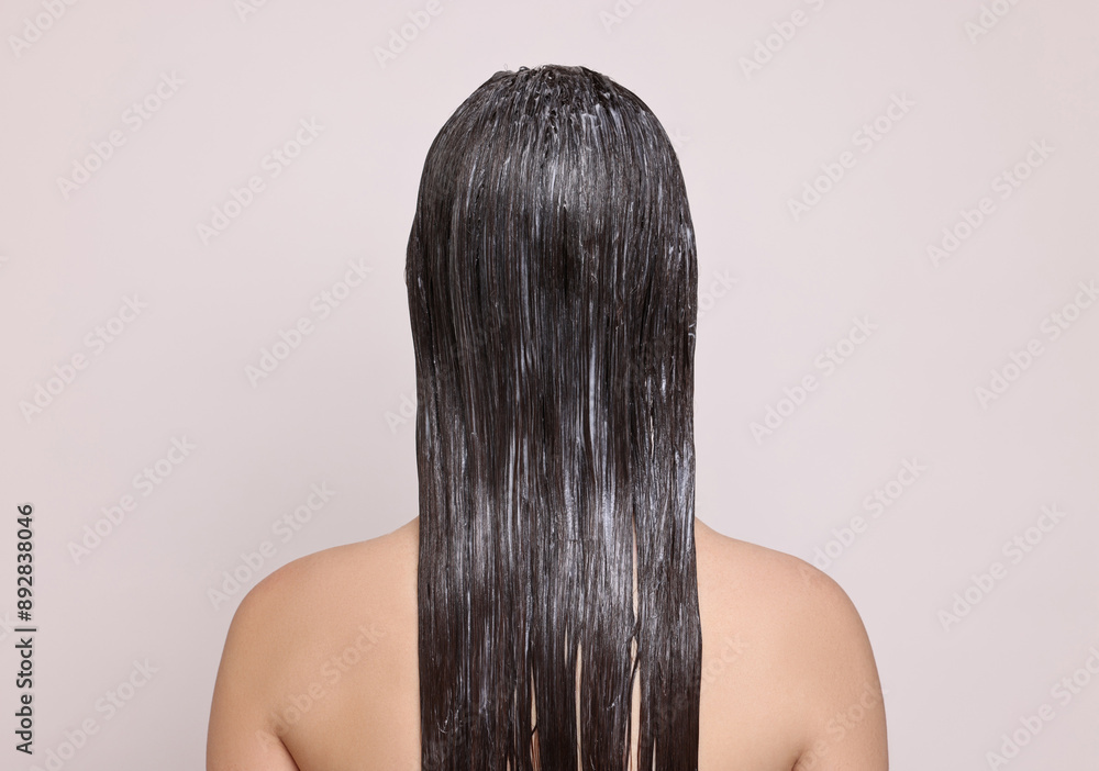 Naklejka premium Woman with applied hair mask on light background, back view