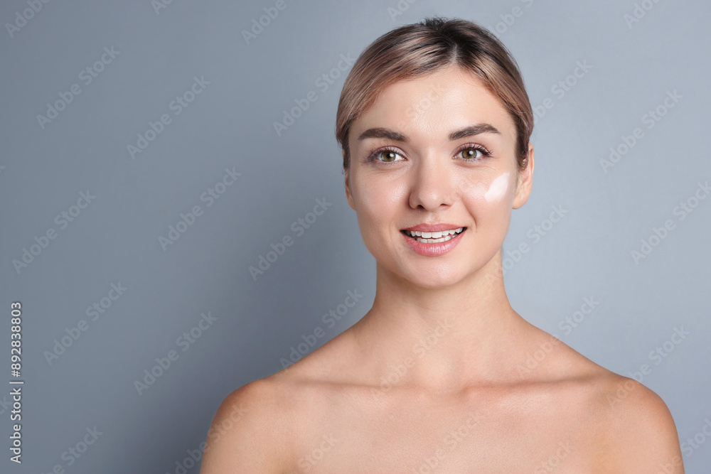 Beautiful woman with cream on her face against gray background Beautiful woman with cream on her face against gray background