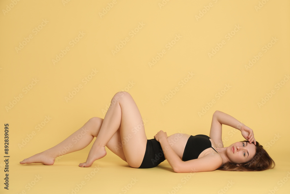 Woman with slim body posing on yellow background Woman with slim body posing on yellow background