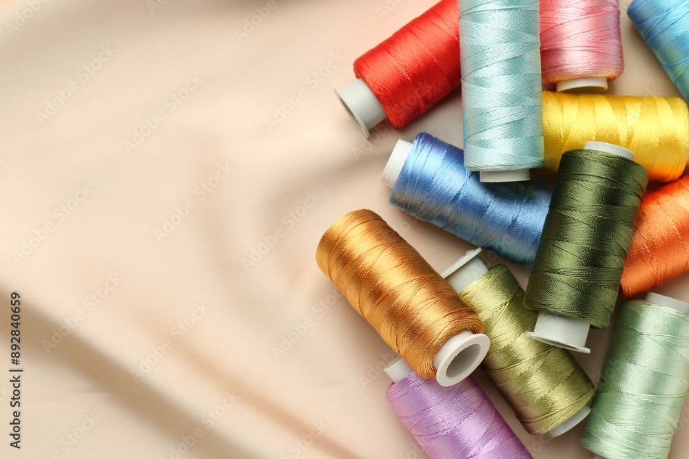 Spools of sewing threads on beige cloth, top view. Space for text Spools of sewing threads on beige cloth, top view. Space for text