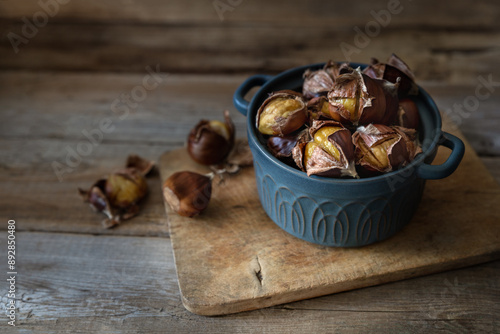 Unpeeled roasted chestnuts on wooden table photo