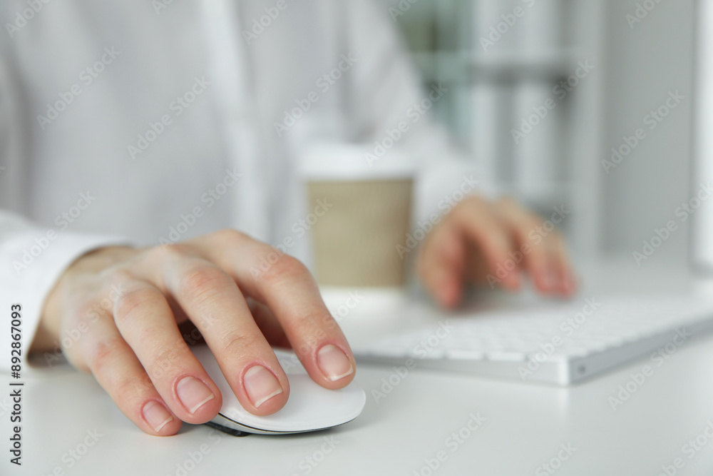 Woman with wireless mouse and paper cup at white table indoors, closeup Woman with wireless mouse and paper cup at white table indoors, closeup