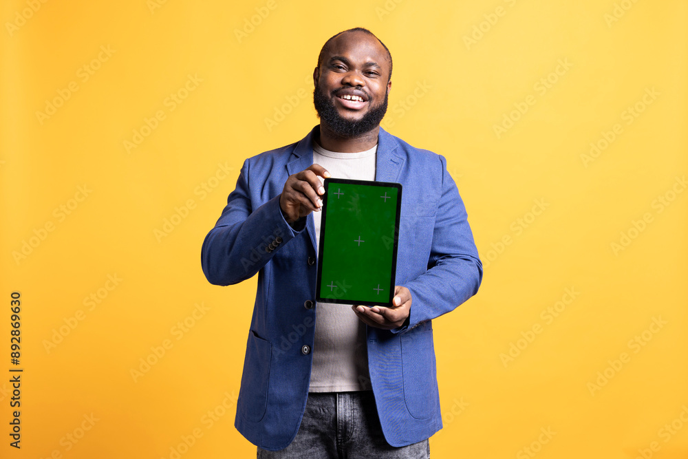 Portrait of man doing influencer marketing using isolated screen tablet, showing positive emotion, studio background. Merry BIPOC person holding empty copy space mockup portable gadget Portrait of man doing influencer marketing using isolated screen tablet, showing positive emotion, studio background. Merry BIPOC person holding empty copy space mockup portable gadget