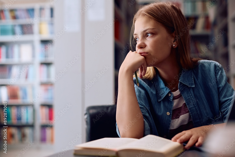 Pensive college student learning for upcoming exams in a library. Pensive college student learning for upcoming exams in a library.