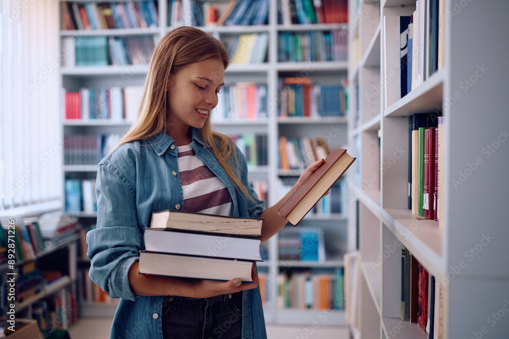 Happy female student choosing books in library at campus. Happy female student choosing books in library at campus.