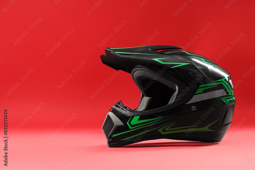 Fototapeta premium Modern motorcycle helmet with visor on red background. Space for text