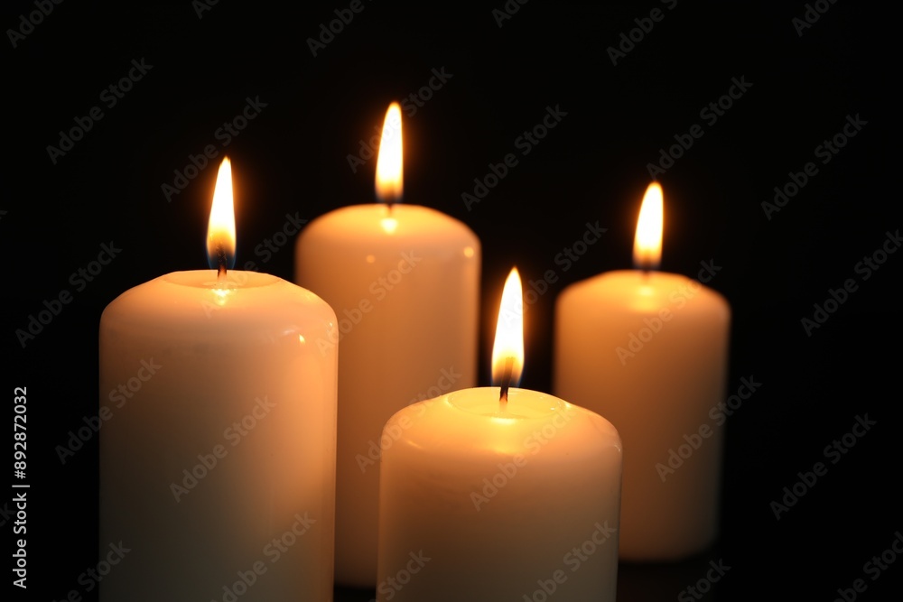 Many burning candles on black background, closeup Many burning candles on black background, closeup