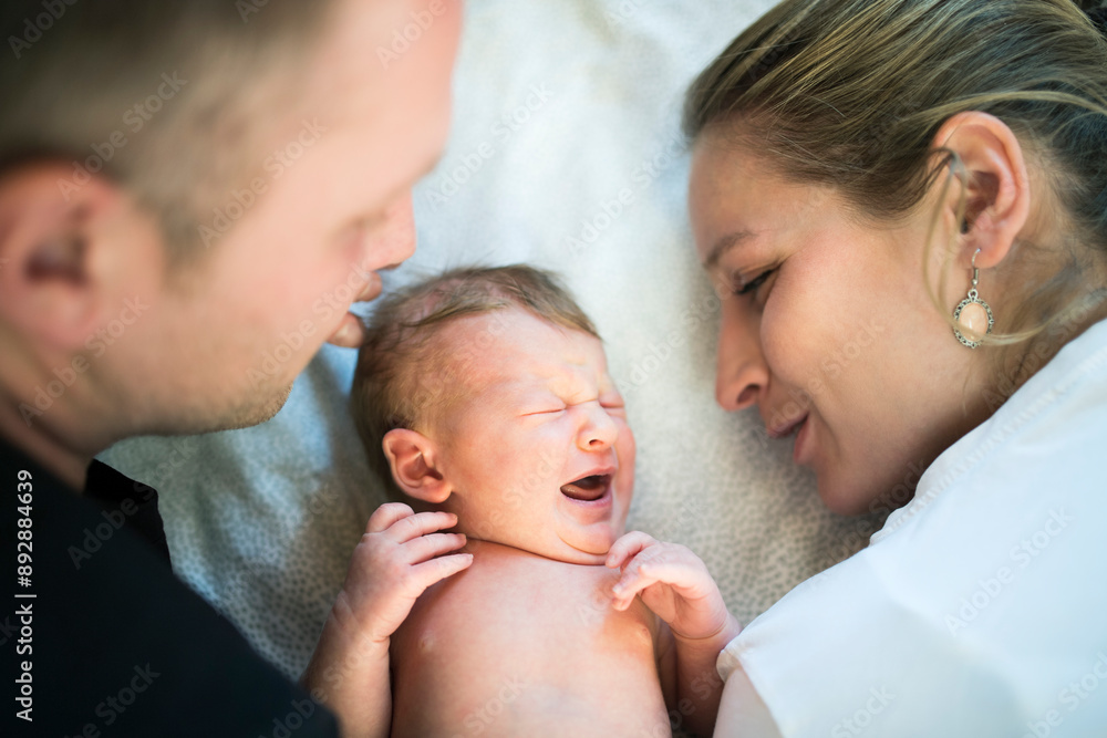 New parents holding newborn crying baby girl. Unconditional paternal love, idyllic family moment. New parents holding newborn crying baby girl. Unconditional paternal love, idyllic family moment.