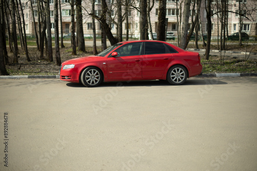 Red car in the parking lot. The car is standing on the asphalt. Transport on the street.