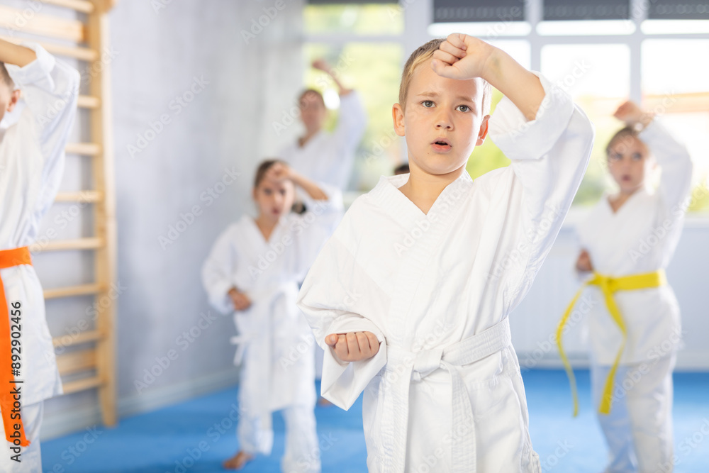 Obraz premium In gym, certified master coach conducts karate kata lesson with children boys girls team students group and shows sequence of actions when conducting close fight