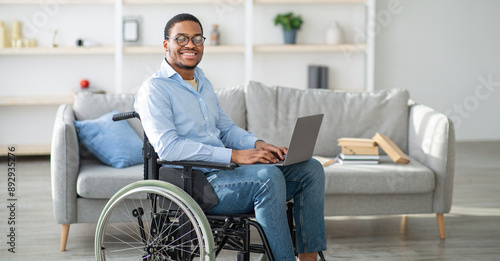 Εκτύπωση καμβά Happy disabled black man in wheelchair using laptop, working online from home, copy space