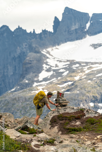 young blonde bearded backpacker and hiker tourist and photographer in Norway taking pictures of the stunning landscape