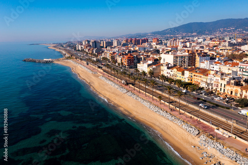 Scenic aerial view of coastal area of Spanish city of Vilassar de Mar overlooking brownish roofs of buildings and sandy seashore on sunny winter day, Catalonia photo