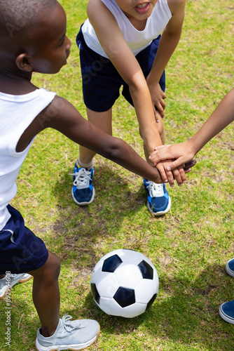 Принти на полотні A group of young friends gathers hands over a soccer ball at school