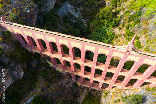 Scenic aerial view of Aqueduct of Eagle, four storied arch bridge over canyon of Barranco de la Coladilla on sunny fall day, Nerja, Spain.. photo