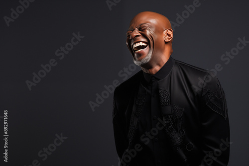 Stylish Senior African-American man in his 60s with a bald head, laughing off camera and Happy about retirement.