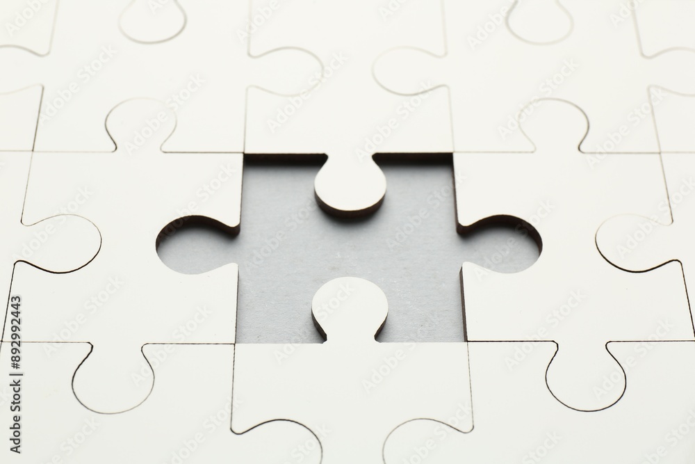 White puzzle with missing piece on grey background, closeup White puzzle with missing piece on grey background, closeup