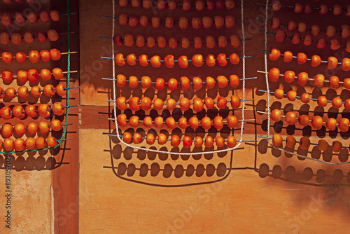 Autumnal view of Gotgam(dried persimmon) hanging and being dried under eaves of a thatched house at Oeam Folk village of Oeam-ri near Asan-si, South Korea
 photo