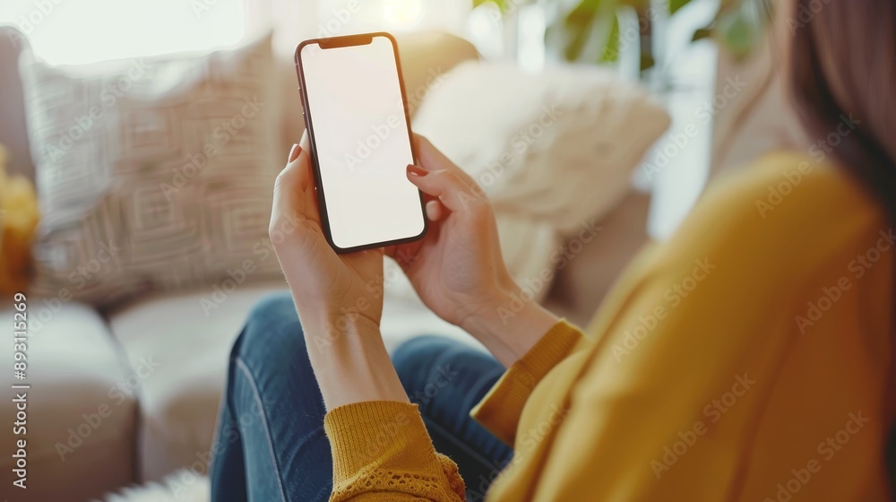 Young woman indoors using smartphone with blank screen for texting on blurred white background Young woman indoors using smartphone with blank screen for texting on blurred white background