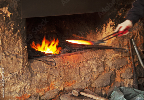 Naganeupseong Folk village, Suncheon-si, South Korea - November 25, 2010: A male blacksmith is holding and heating an iron knife on fire flame at Blacksmith's Shop
 photo