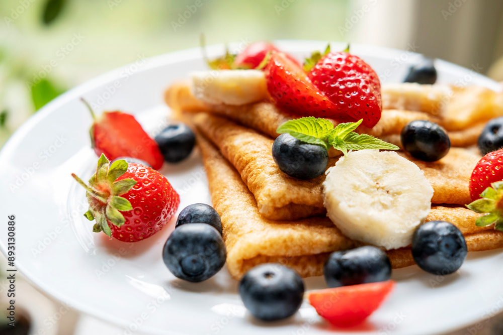 Thin pancakes in a plate with berries. Useful and tasty breakfast or snack. Thin pancakes in a plate with berries. Useful and tasty breakfast or snack.