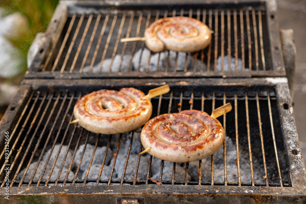 Barbecue in the garden. Bratwurst rolls (grilled sausage or ring sausage) on a skewer on the grill. Close-up Barbecue in the garden. Bratwurst rolls (grilled sausage or ring sausage) on a skewer on the grill. Close-up