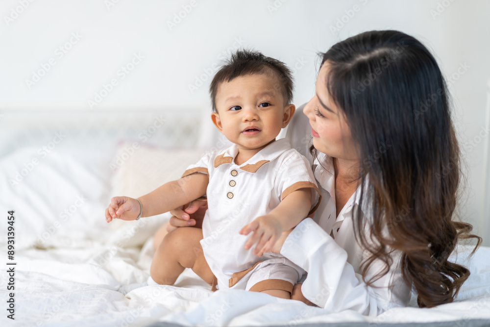 Portrait of enjoy happy love family asian mother playing with adorable little asian baby.Mom touching with cute son moments good time in a white bedroom.Love of family concept Portrait of enjoy happy love family asian mother playing with adorable little asian baby.Mom touching with cute son moments good time in a white bedroom.Love of family concept