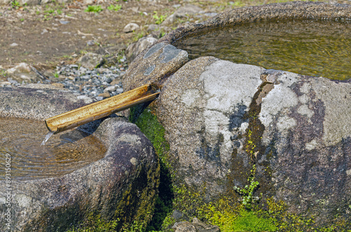 Seungju-eup, Suncheon-si, South Korea - April 9, 2011: Morning view of mineral spring water flowing through a bamboo pipe between two stone mortars at backyard of Seonamsa Temple
 photo