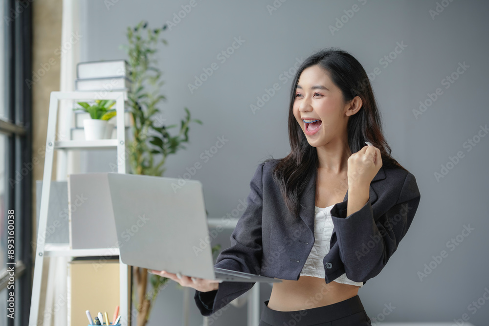 Young businesswoman is happy with something she sees on her laptop, possibly good sales figures or a positive business email Young businesswoman is happy with something she sees on her laptop, possibly good sales figures or a positive business email