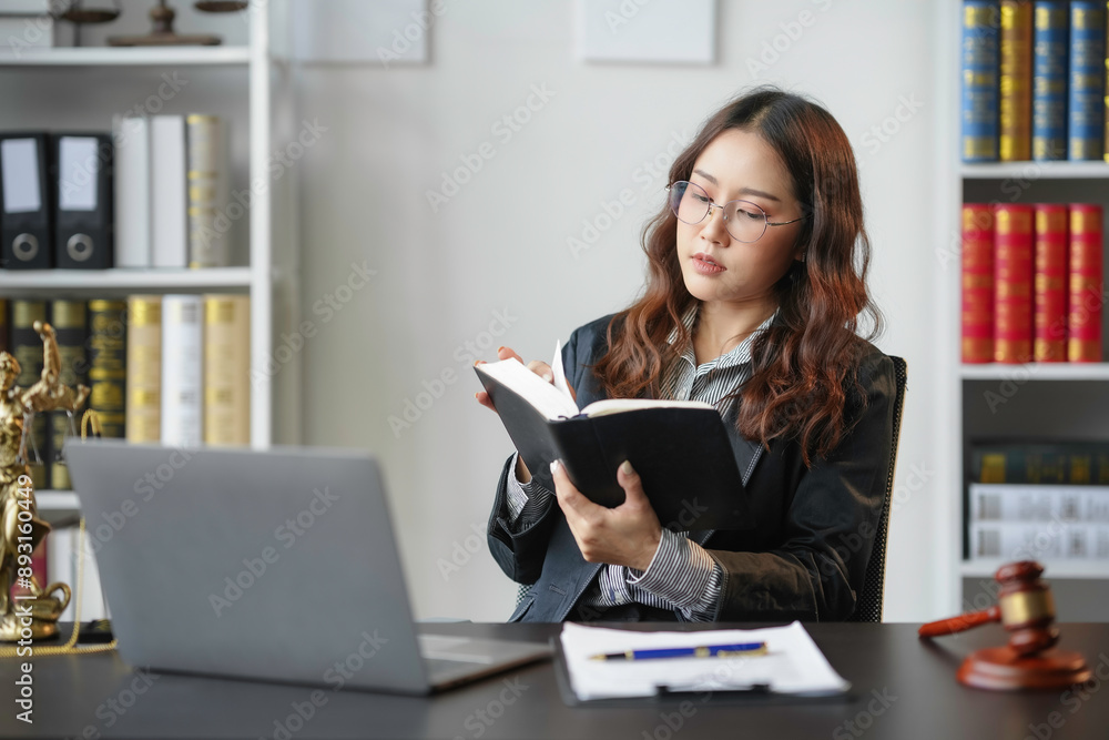 Lawyer is sitting at her desk in her office, surrounded by law books and a laptop, deeply engrossed in a law book while preparing for an upcoming case Lawyer is sitting at her desk in her office, surrounded by law books and a laptop, deeply engrossed in a law book while preparing for an upcoming case