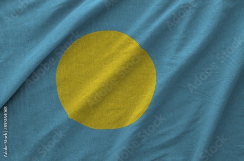 Palau flag depicted on folded wavy fabric of old cloth close up photo