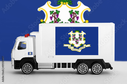 Connecticut US state flag depicted on side wall of white delivery van close up. Shipping and local delivery concept photo