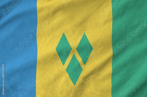 Saint Vincent and the Grenadines flag depicted on folded wavy fabric of old cloth close up photo