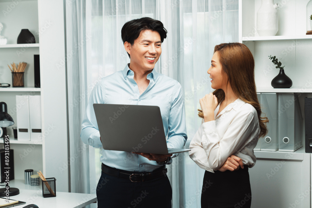 Smiling Asian coworkers standing while talking planning marketing report project on laptop casual day at modern office. Analyzing successful customer need in new social media online channel. Infobahn. Smiling Asian coworkers standing while talking planning marketing report project on laptop casual day at modern office. Analyzing successful customer need in new social media online channel. Infobahn.