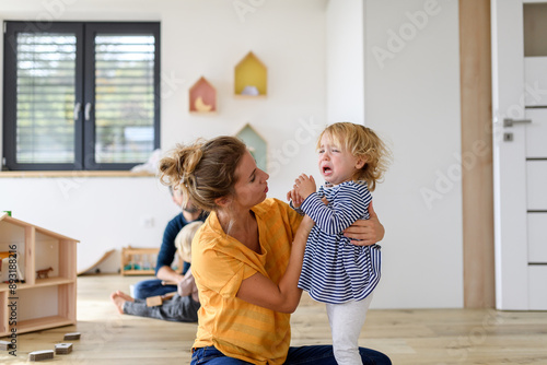 фотографія Little girl crying and screaming, mother holding her in arms and soothing her