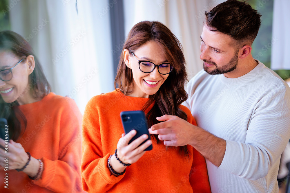 Happy couple standing together at home and using a smartphone Happy couple standing together at home and using a smartphone