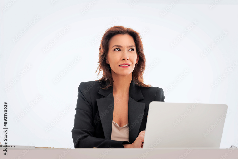 Studio portrait of a mid age businesswoman sitting at desk against isolated background Studio portrait of a mid age businesswoman sitting at desk against isolated background