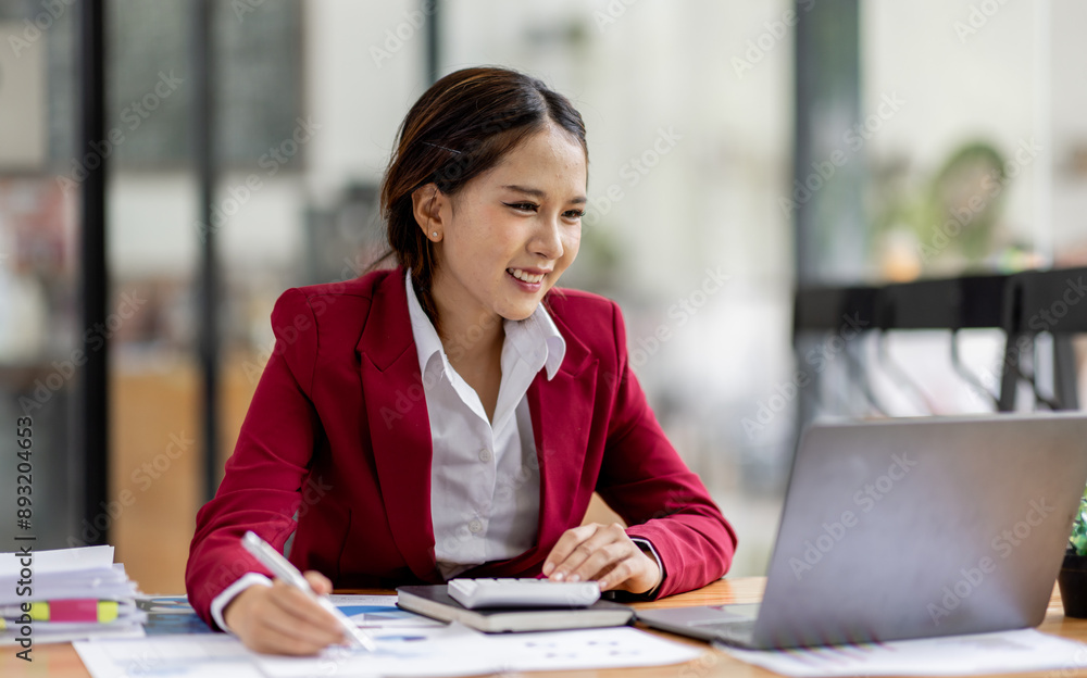 Business asian woman working on laptop, using financial calculator at modern office, analyzing business document with financial graph, market report on digital tablet, business data analysis concept Business asian woman working on laptop, using financial calculator at modern office, analyzing business document with financial graph, market report on digital tablet, business data analysis concept