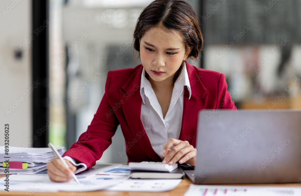 Business asian woman working on laptop, using financial calculator at modern office, analyzing business document with financial graph, market report on digital tablet, business data analysis concept Business asian woman working on laptop, using financial calculator at modern office, analyzing business document with financial graph, market report on digital tablet, business data analysis concept