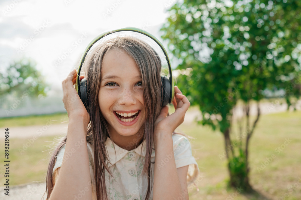 Cheerful long hair girl wearing wireless headphones and enjoying music at back yard Cheerful long hair girl wearing wireless headphones and enjoying music at back yard