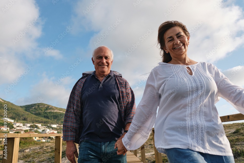 Smiling couple holding hands and having fun under cloudy sky Smiling couple holding hands and having fun under cloudy sky
