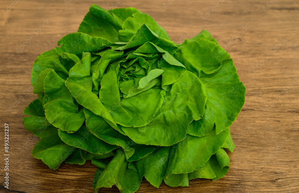 Salata głowiasta masłowa pojedyncza izolowana leży na drewnianym stole, z bliska Salata głowiasta masłowa pojedyncza izolowana leży na drewnianym stole, z bliska