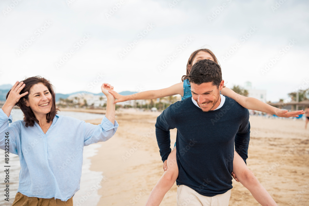 Happy woman with father giving piggyback ride to daughter at beach Happy woman with father giving piggyback ride to daughter at beach